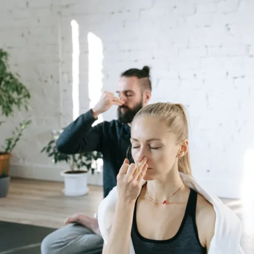 Breathing in Postures: A Guide to Breathing through Asanas; a man and a woman holding their noses for breathing control exercise