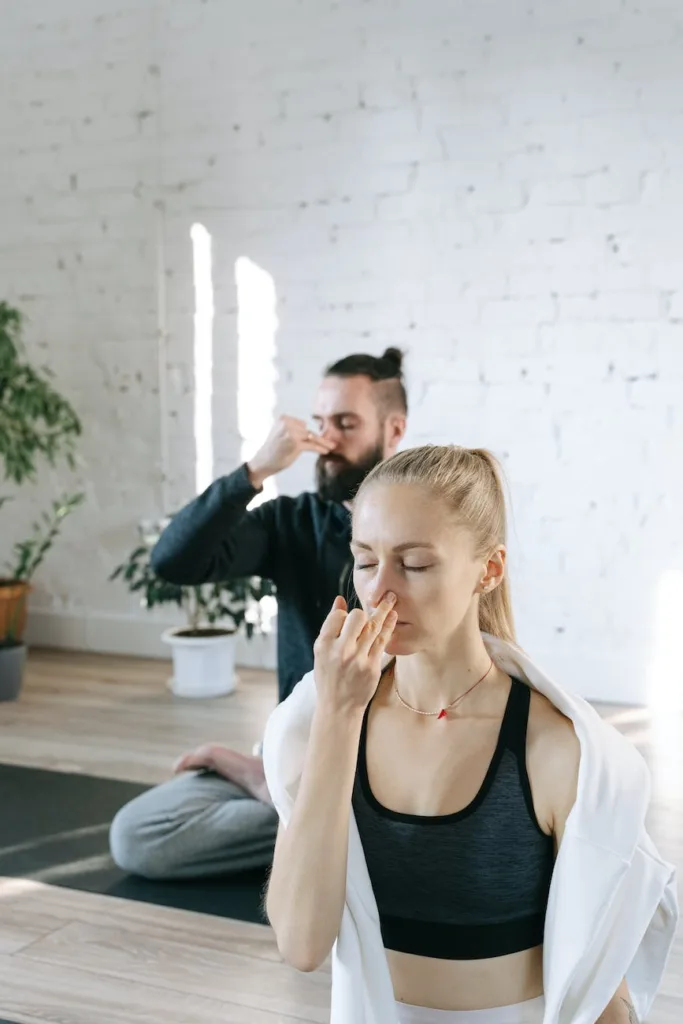 Breathing in Postures: A Guide to Breathing through Asanas; a man and a woman holding their noses for breathing control exercise
